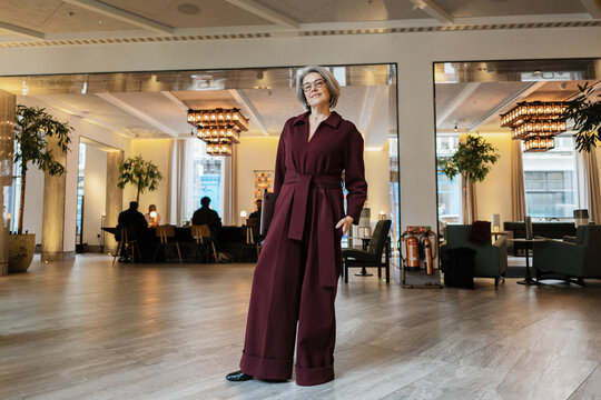 Professional senior woman wearing jumpsuit in modern hotel lobby