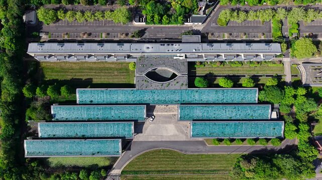 Aerial view of the Bp Pulse Charging Station featuring solar panel roofs and modern architecture surrounded by green trees in Coventry, England, United Kingdom.