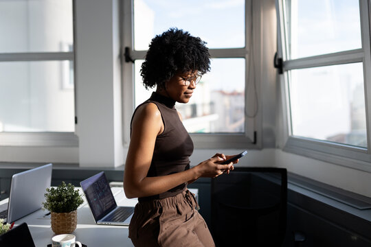 Woman using phone in modern office workspace