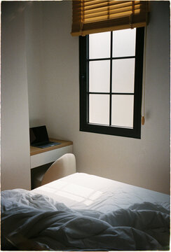 Cozy bedroom with desk and window during day time