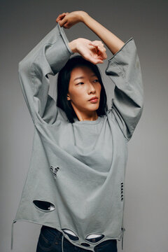 Person modeling oversized distressed fashion clothing in studio