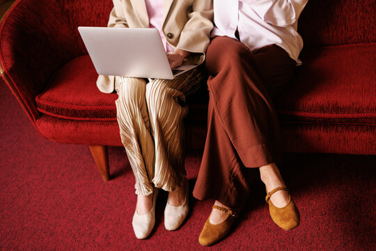 Women business team with laptop in office on red sofa