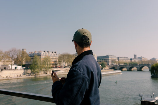 A tourist admiring the cityscape from a bridge over the Seine River