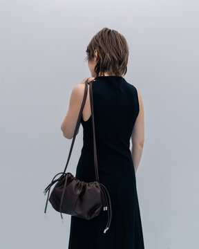 Back view of woman in black dress with leather shoulder bag