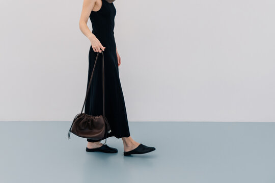 Unrecognizable Woman in Black Dress Walking Across Blue Floor