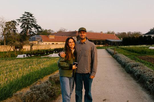 A happy couple smiles in a Parisian country hotel garden at sunset