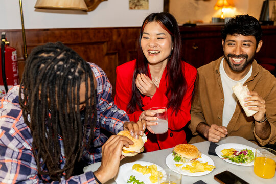 Group of Friends hanging out at restaurant eating hamburgers 