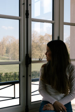 Woman sitting on a window ledge, admiring the natural scenery