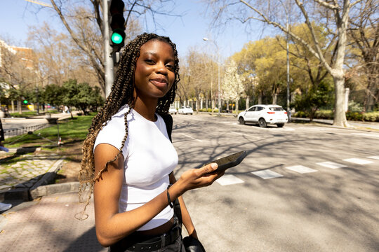 Woman using smartphone walking on the city looking at camera