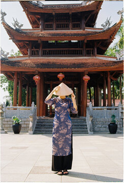 Woman in traditional clothing stands in front of  the temple