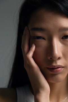 Asian person touching face with thoughtful expression