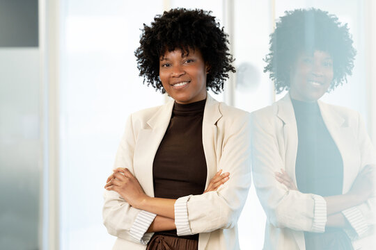 Black businesswoman smiling with arms crossed in office