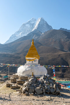 Buddhist stupa with prayer flags below snow covered Himalayan peak