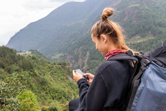 Female hiker checking smartphone during mountain trek