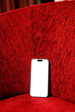 Blank smartphone mockup with white screen on red sofa