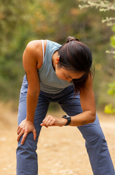 Asian woman athlete trail  runner Looking smartwatch 