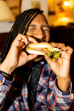 Man eating hamburger at restaurant. Direct flash
