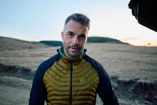 Man stands in the field at sunset, looking at the camera