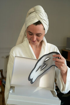 Woman Opens Box While Wearing a Towel on Her Head at Home