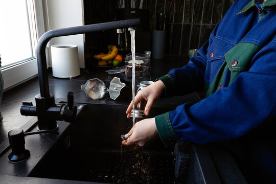 A woman is washing a coffee pot.