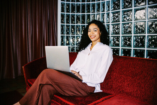 Business woman portrait with laptop on red sofa in modern interior