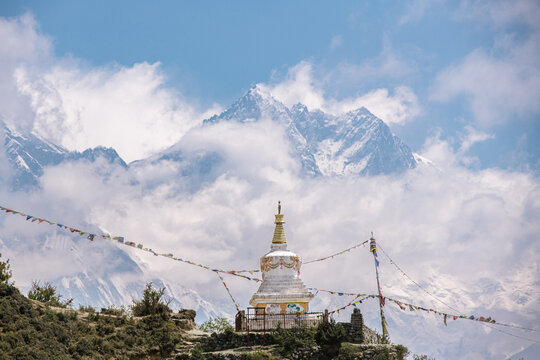 Buddhist stupa with prayer flags beneath snow covered Himalayan peaks