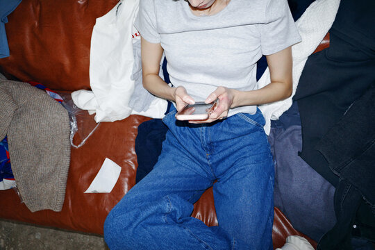 Person relaxing on couch using smartphone for communication