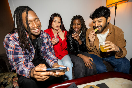 Group of Friends hanging out at home party checking smartphone