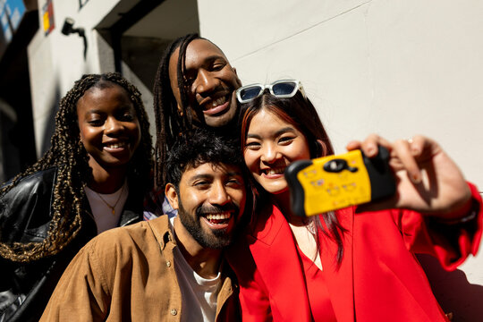 Group of friends taking a selfie with disposable camera in the street