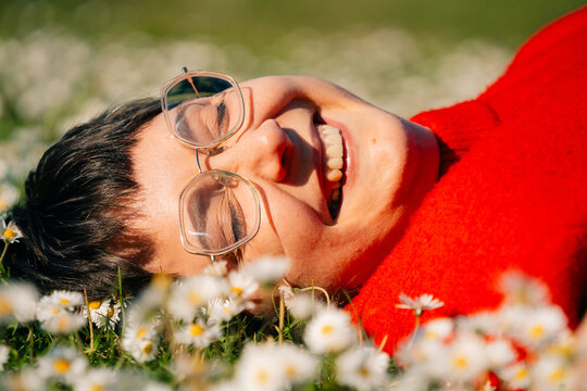 Person Lies in a Field of Flowers and Smiles Brightly in Sunlight
