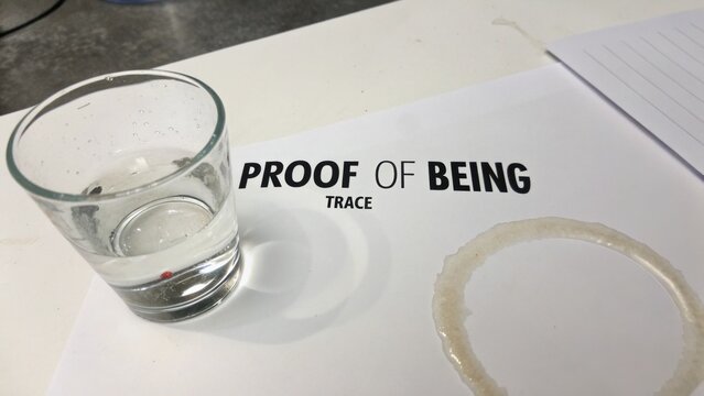 Glass of water on document with words "Proof of Being" and a water ring stain showcasing a visual representation of existence and evidence