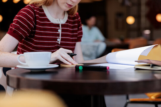 Woman at cafe table writing notes with coffee.