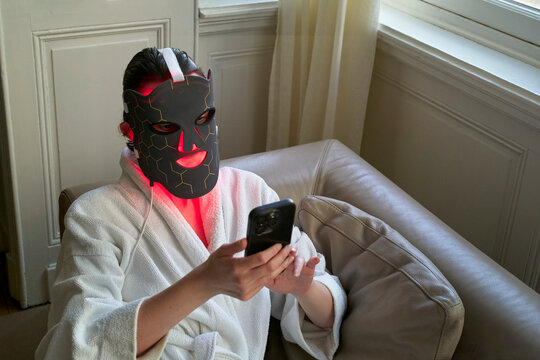 Woman Using Skincare Mask While Sitting on Couch With Phone