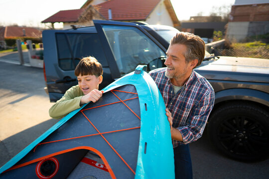 Father and son preparing a windsurf board outside