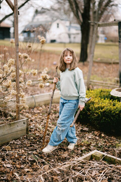little girl smiling while holding walking stick on spring day