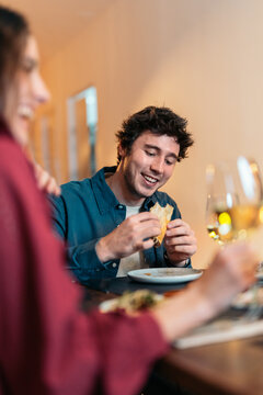 Happy man eating taco in restaurant with partner