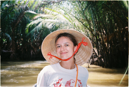 Woman in a boat on a river surrounded by trees in a tropical island.