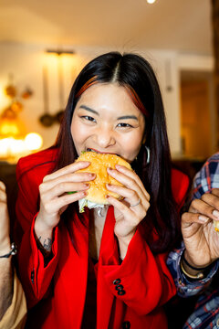Woman eating hamburger at restaurant looking at camera Direct flash