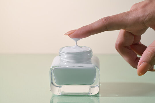 Woman's finger touching cream from a jar, skincare and beauty concept