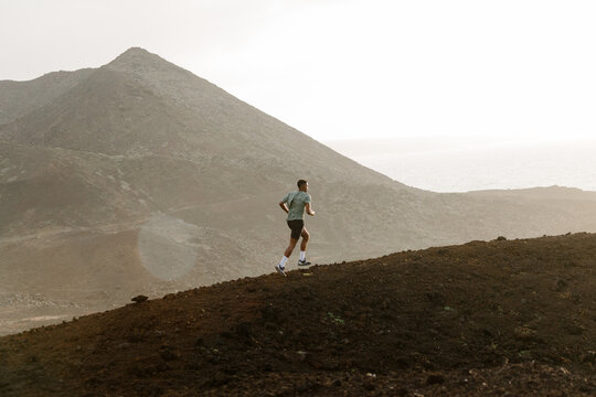 Volcanic landscape, with a trail runner training in the distance