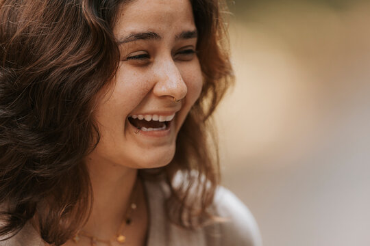 Young woman laughing outdoors, expressing joy and happiness