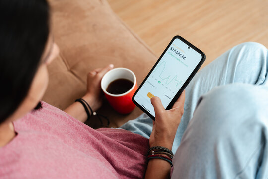 Young Person Checking Investment App on Smartphone at Home