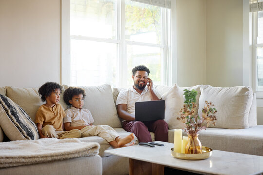 Father working from home while his children watch TV