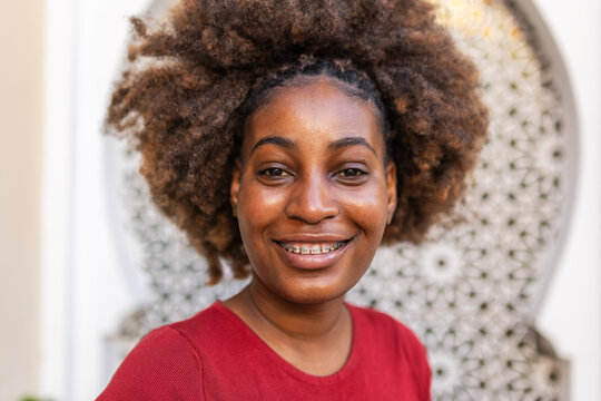Portrait of a young black woman with afro hair and braces