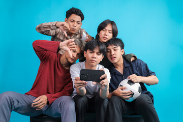 Fototapeta premium Disappointed Young Asian Men Giving Thumbs Down Gesture While Watching Losing Football Match