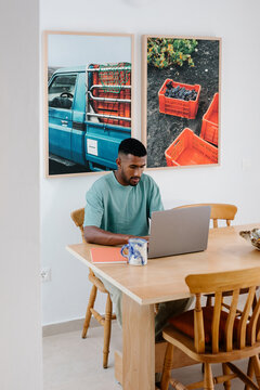 Online business owner in a dining room, working on a computer