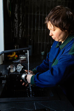 A woman is washing a coffee pot.