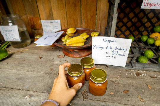 UGC POV Hand reaching for jars of chutney at roadside fruit stall.