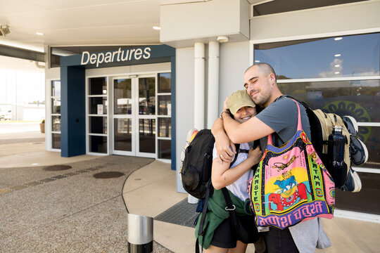 Couple embracing outside small airport departures entrance