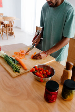 Unknown man chops fresh vegetables while preparing a nutritious food